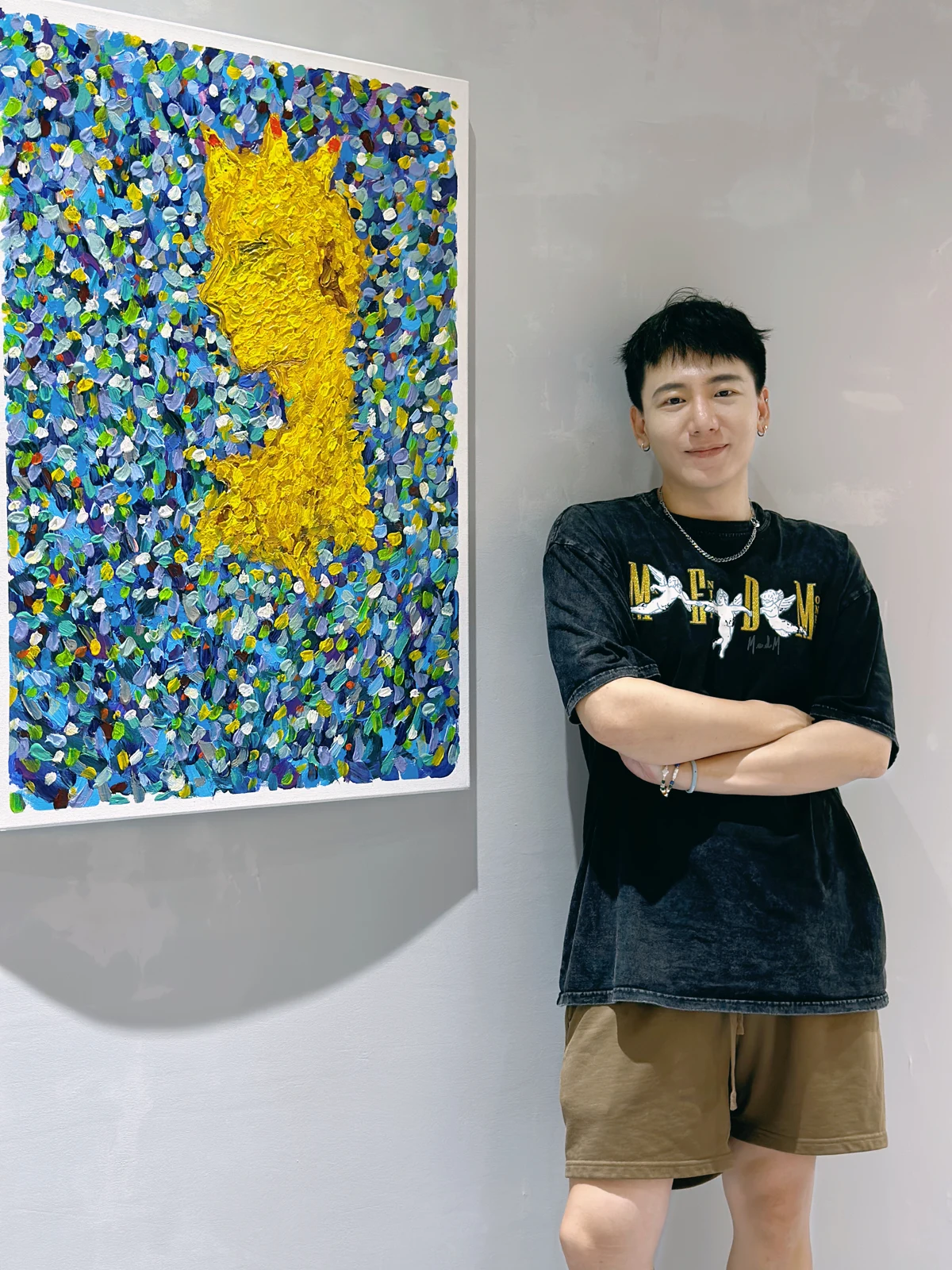 Du Haha standing beside a blue and yellow painting at his exhibition